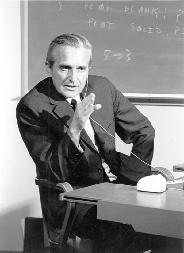 Douglas Engelbart during the 1968 Mother of All Demos, with an early mouse on the desk in front of him.