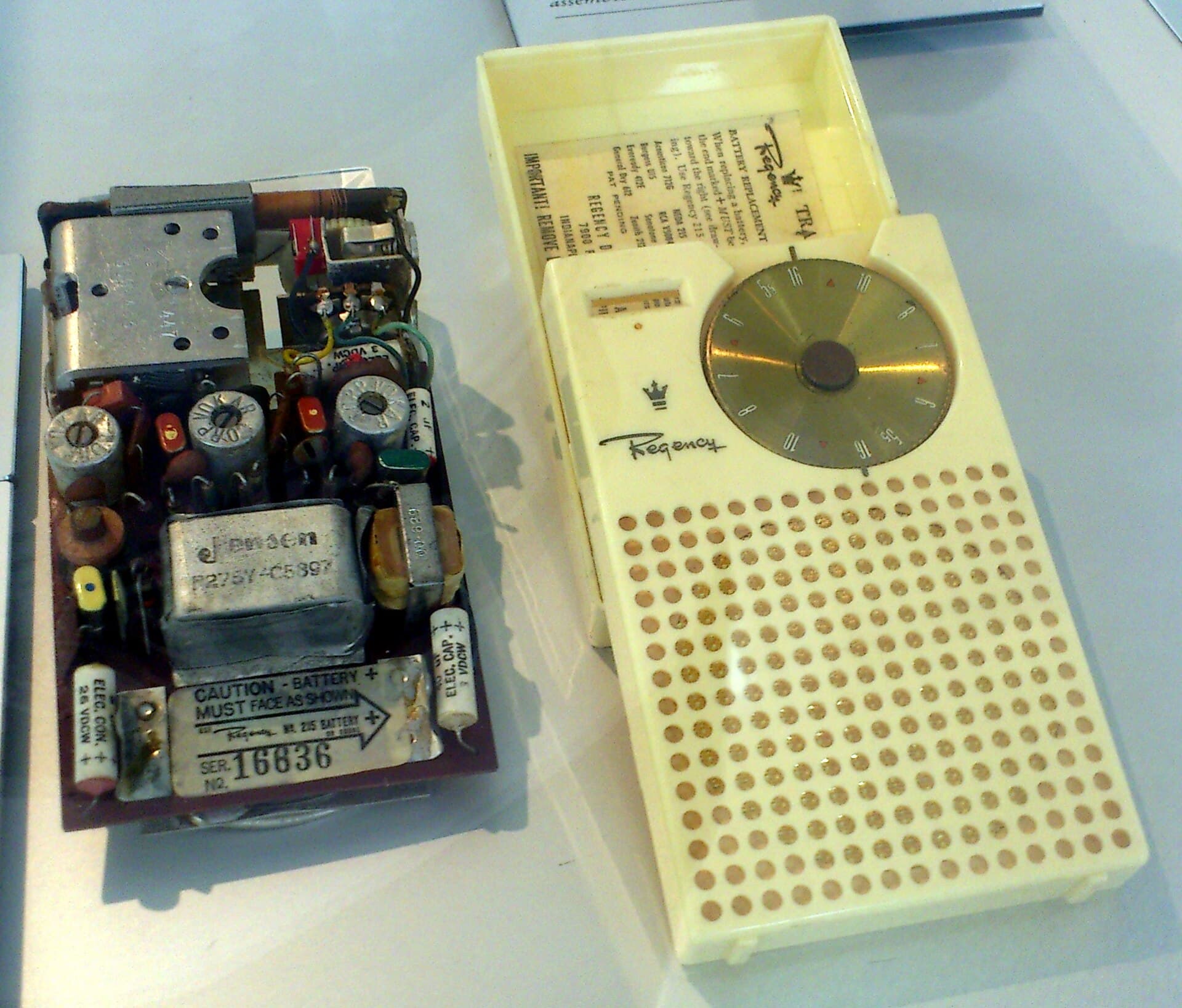 A Regency TR-1 transistor radio, opened beside its case.